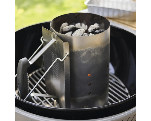 Weber Anzündkamin aus Edelstahl mit Griff in einem Kugelgrill auf dem Grillrost platziert für Holzkohle und Briketts.