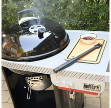 Weber Holzkohlegrill Performer mit Grillwagen, Seitenablage, Grillbesteck und Schale auf einer Terrasse