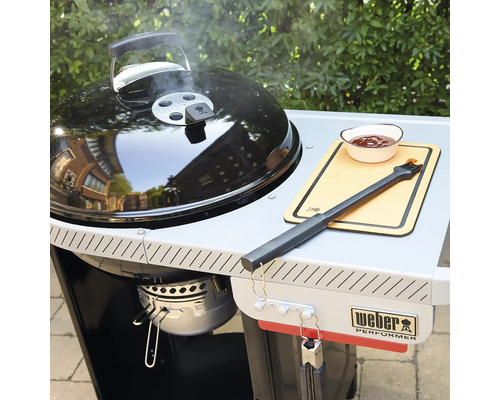 Weber Holzkohlegrill Performer mit Grillwagen, Seitenablage, Grillbesteck und Schale auf einer Terrasse