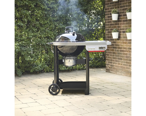 Weber Performer Holzkohlegrill mit Arbeitstisch auf einer Terrasse stehend.