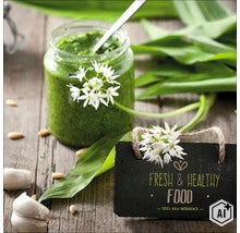 Ein Glas Bärlauchpesto mit frischen Bärlauchblättern, Blüten, Knoblauchzehen und Pinienkernen auf einer Holzoberfläche mit einem Schild. (Image AI modified or generated)