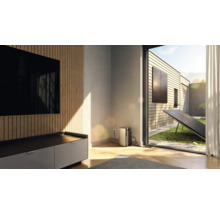 Balkonkraftwerk mit Speicher verbunden in einem hellen Wohnzimmer mit Blick auf eine Terrasse und Garten mit Solarmodul.