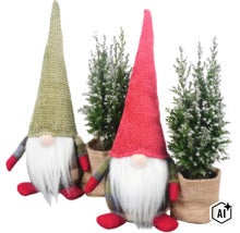 Zwei dekorative Wichtel mit hohen Mützen und zwei künstliche kleine Tannenbäume in Jutetöpfen als Weihnachtsdekoration. (Image AI modified or generated)