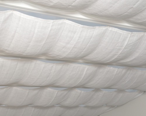 Detailaufnahme von gerafften, weißen Stoffbahnen unter einer Decke, Teil einer textilen Raumgestaltung