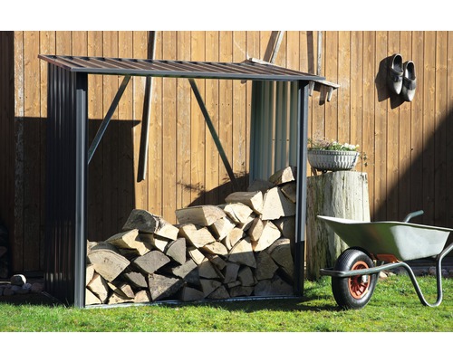 Holzlager mit Brennholz und Schubkarre im Garten