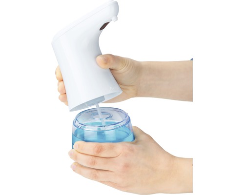 Hände befüllen einen berührungslosen Seifenspender mit Flüssigseife