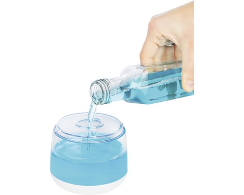 Eine Hand gießt blaue Flüssigkeit aus einer Flasche in einen Spender.