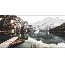 Bergsee mit Holzbooten und Steg vor Bergkulisse
