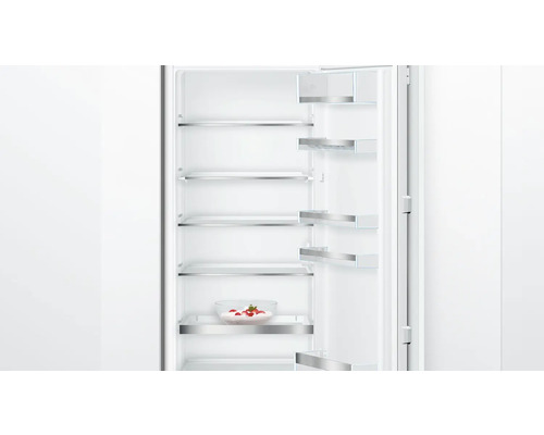 Geöffneter Kühlschrank mit mehreren Regalböden und einer Schüssel mit Erdbeeren.