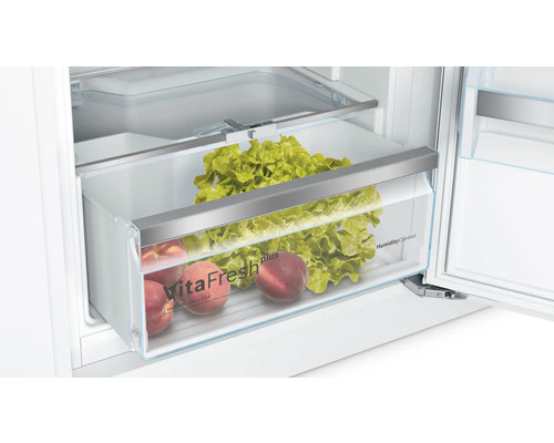 Innenraum eines Kühlschranks mit Gemüsefach, gefüllt mit Salat und Pfirsichen