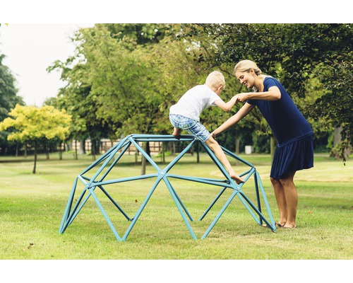 Mutter hilft Kind beim Klettern auf einem Klettergerüst im Freien.