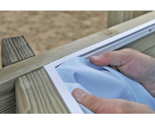 Handwerker montiert eine weiße Fensterdichtung an einem Holzfenster