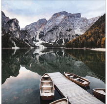 Landschaft mit See, Bergen und Holzbooten an einem Steg