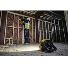 Baustellenszene mit Arbeiter, der mit einer Akku-Lampe arbeitet