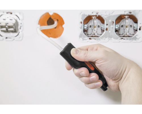 Eine Hand hält einen Wiha Spannungsprüfer vor einer Steckdose.