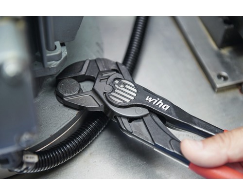 Wiha Logo. Zange im Einsatz an einer Schraube.