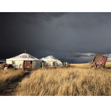 Szene mit mongolischen Jurten und einem hölzernen Wagen auf einem Feld unter einem dunklen Himmel.