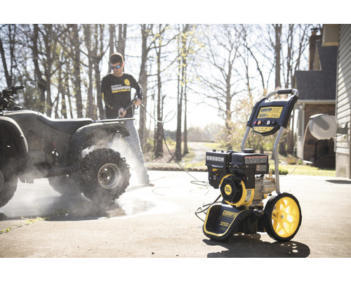 Mann reinigt ein Quad mit einem Hochdruckreiniger im Freien.