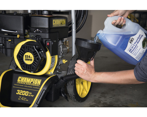 Eine Person füllt Reinigungsflüssigkeit in einen Champion Hochdruckreiniger.