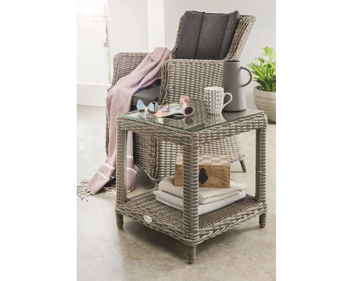 Gartenszene mit Rattansessel und Beistelltisch mit Glasplatte