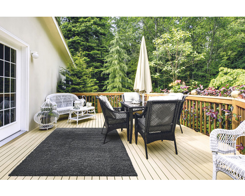 Terrasse mit Rattanstühlen, Tisch, Sonnenschirm und Teppich