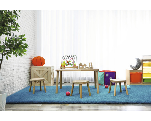 Helles Kinderzimmer mit Holztisch, Hockern und Spielzeug auf einem blauen Teppich.