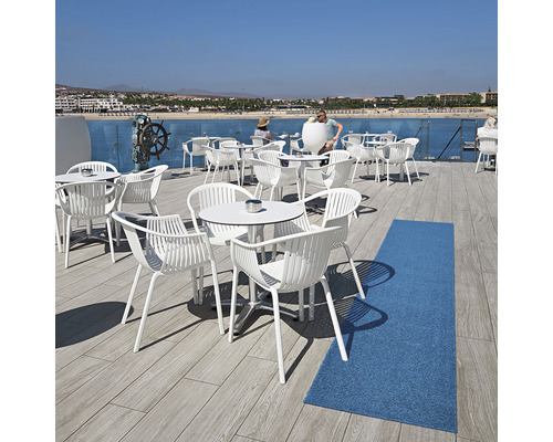 Terrasse mit weißen Gartenmöbeln, Tischen und Stühlen mit Meerblick.