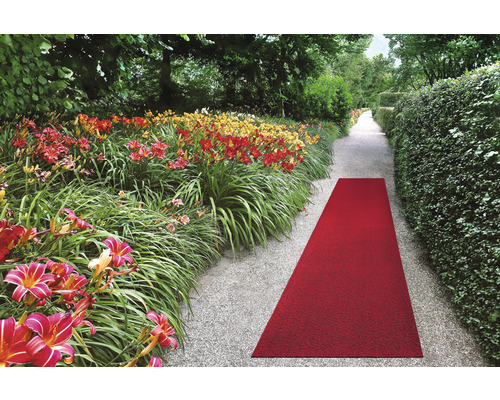Roter Teppichläufer im Gartenweg zwischen Blumenbeeten und Hecken