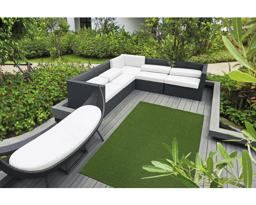 Gartenszene mit modularem Lounge Set, Liegestuhl und Kunstrasen auf einer Terrasse