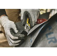 Eine Person schneidet Dachpappe mit einem Stanley Cuttermesser.