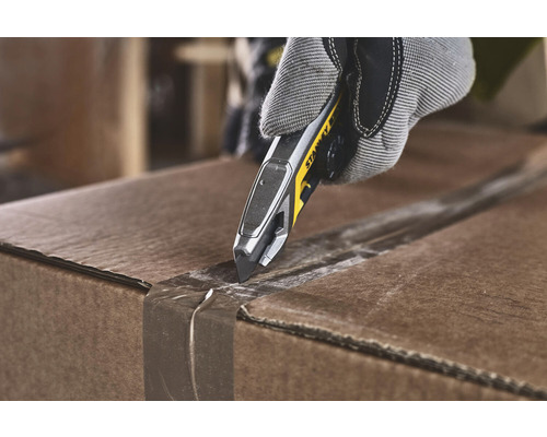 Eine Hand mit Arbeitshandschuh öffnet einen Karton mit einem Stanley Messer.