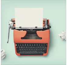Orangefarbene Schreibmaschine mit einem Blatt Papier und Papierknäueln
