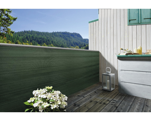 Balkon mit Sichtschutz, Holzdielen und Kommode vor Bergkulisse