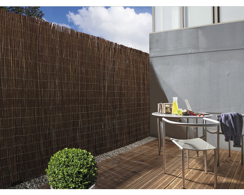 Szene mit einer Terrasse, die mit einem Sichtschutzzaun und Gartenmöbeln ausgestattet ist.