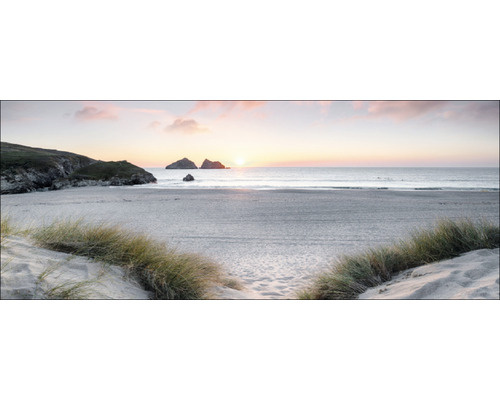 Sonnenaufgang über einem ruhigen Sandstrand mit Grasbüscheln