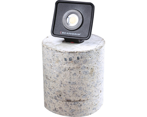 Scangrip Logo. Quadratische Arbeitsleuchte auf Beton.