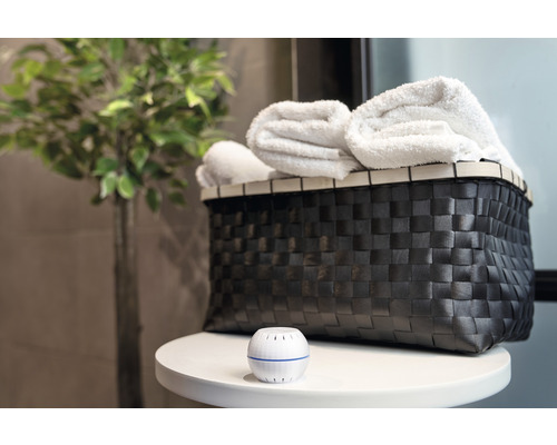 Dekorative Szene mit Korb, Handtüchern und Lufterfrischer auf einem Tisch.