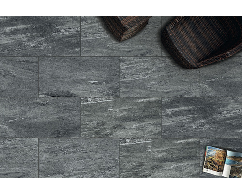 Fliesen mit Steinoptik, zwei Korbsessel und eine Zeitschrift