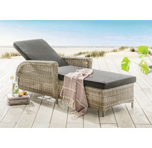 Geflochtene Gartenliege mit grauer Polsterung auf einer Holzterrasse am Strand