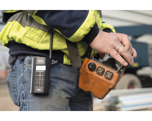 Nahaufnahme eines Mannes mit Funkgerät und Kransteuerung