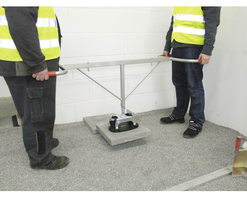 Zwei Bauarbeiter transportieren eine Betonplatte mit einem Vakuumheber.