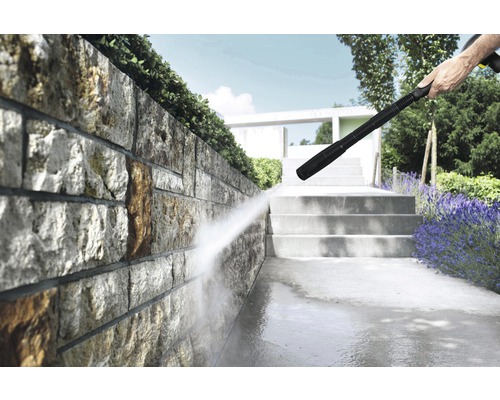 Hochdruckreiniger im Einsatz zur Reinigung einer Steinmauer und eines Gehwegs