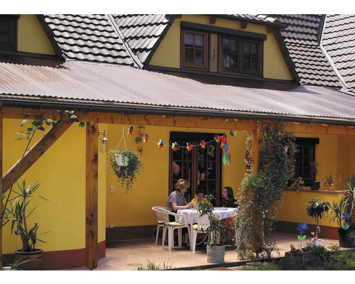 Haus mit überdachter Terrasse, Tisch, Stühlen und dekorativen Pflanzen