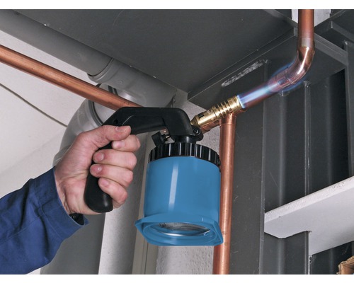 Ein Handwerker lötet mit einem Lötbrenner Kupferrohre.