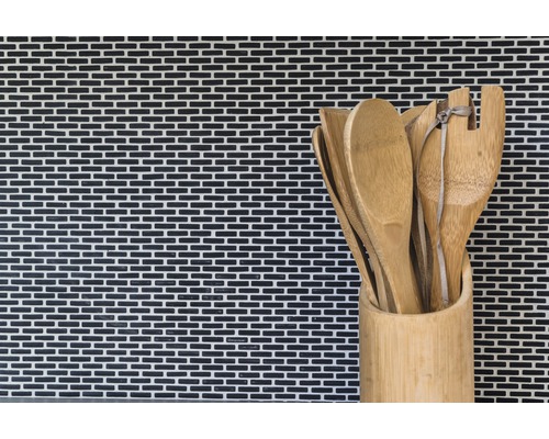 Holzlöffel und Spatel in einem Bambusbehälter vor einer Mosaikwand