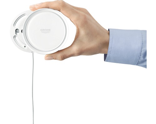 Eine Hand hält einen Grohe Wassersensor.