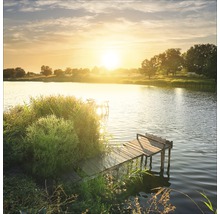 Sonnenaufgang über einem See mit hölzernem Steg und Ufervegetation