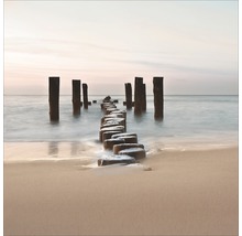 Ansicht einer Holzpfostenreihe im Meer vom Strand aus
