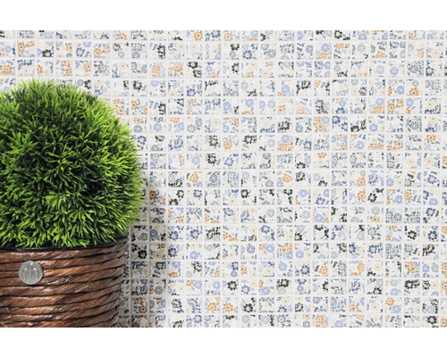 Dekorative Mosaikfliese mit Blumenmuster und Kunstpflanze im Topf.