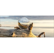 Dekorative Glaskugel auf einem Stück Treibholz am Strand
